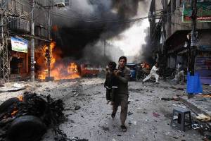 A man and a child flee the site of a blast in Peshawar, Pakistan