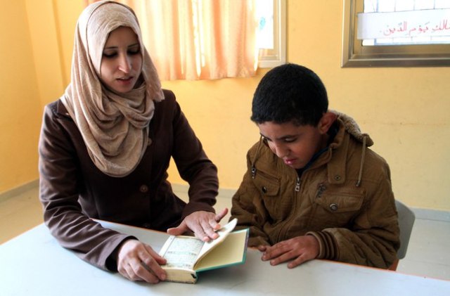Gazze'deki otizm hastalarının rehabilite edildiği özel okulun eğitim uzmanlarından Nedve Abdulal(sol),10 yaşındaki Filistinli Halid Ebu Musa(sağ)'nın otizm hastası olmasına rağmen, sadece bir yılda Kur'an-ı Kerim'i ezberlemesine yardımcı oldu. 07-02-2015 (Abd Rahim Khatib - Anadolu Ajansı)