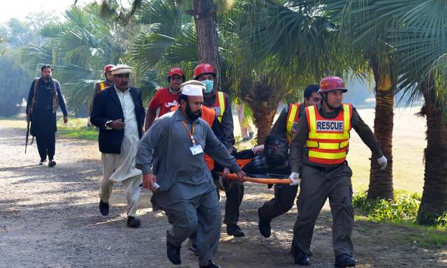 Pakistani army soldiers carry a victim at Bacha Khan university following an attack by militants in Charsadda, about 50 kilometres from Peshawar, on January 20, 2016. At least 21 people died in an armed assault on a university in Pakistan on January 20, where witnesses reported two large explosions as security forces moved in under dense fog to halt the bloodshed. AFP PHOTO / A MAJEED